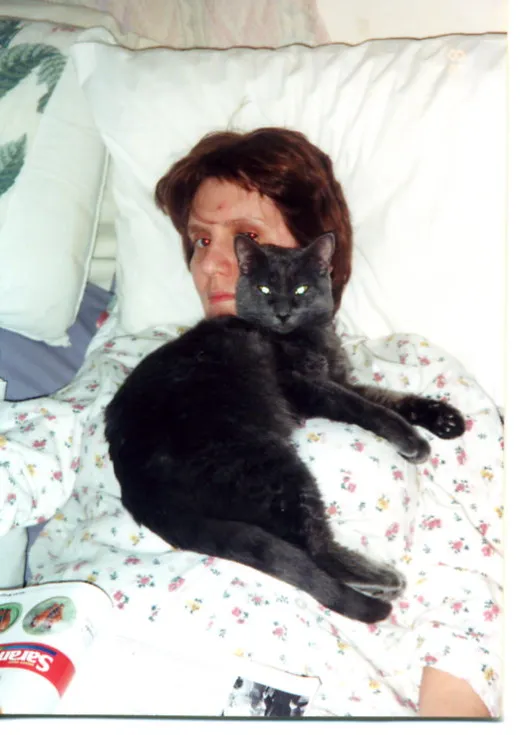 Patti in a hospital bed comforted by her cat